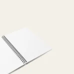 Spiral notebook with whimsical butterfly illustration, featuring artist-designed cover and compact size.